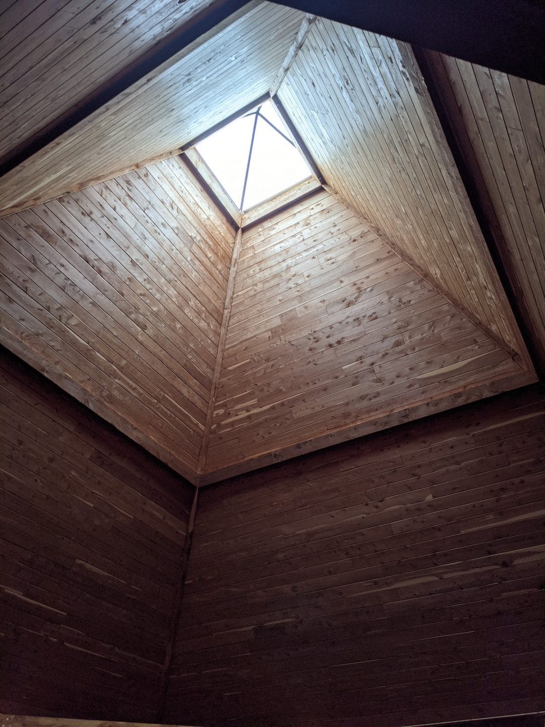 interior view of a pyramid shaped skylight at the peak of a vaulted wooden ceiling
