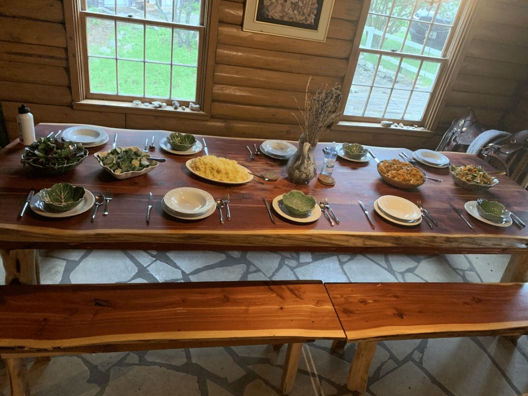 a wooden log dining table with matching benches 10 place settings and bowls of rice and cooked vegetables in a house in North Carolina