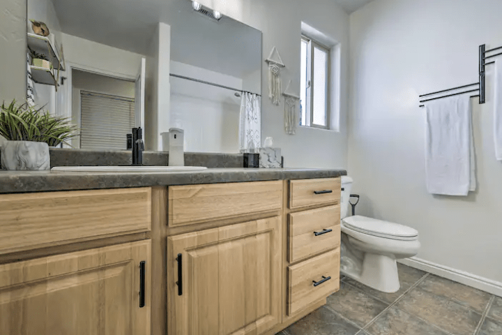 interior of a white bathroom with wood panel cabinets, single vanity sink, and toilet