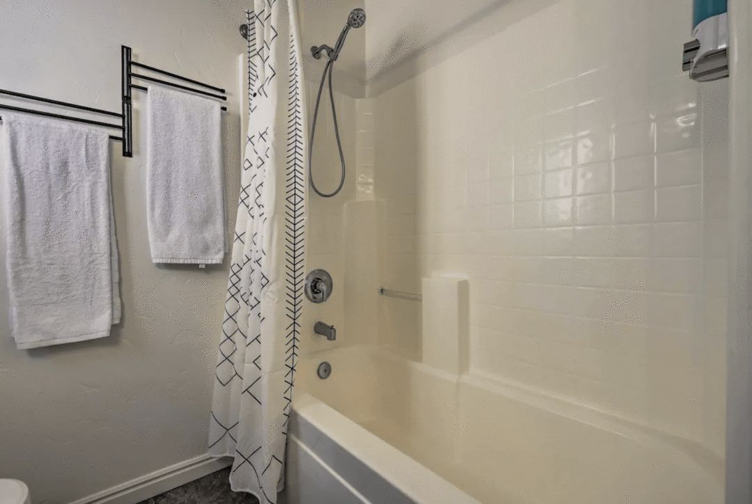 interior of a white bathroom with tub and shower curtain and 2 towel racks hanging on the wall