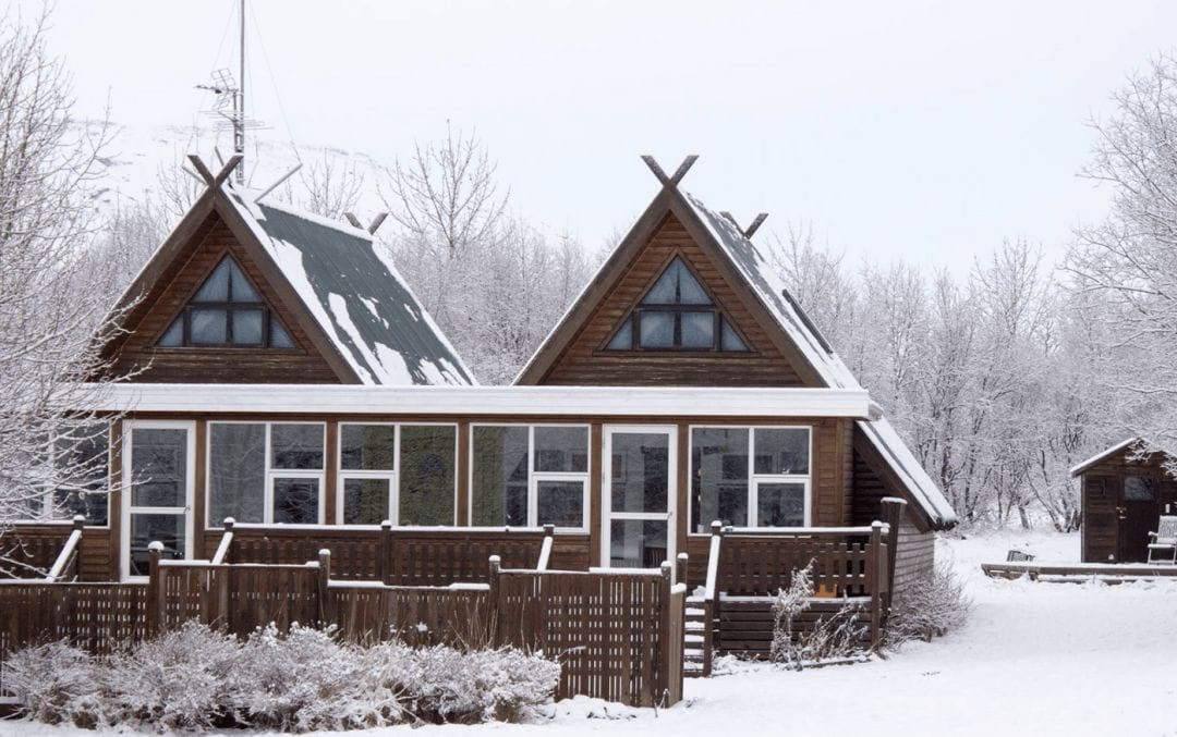 A snow covered house with large enclosed back deck