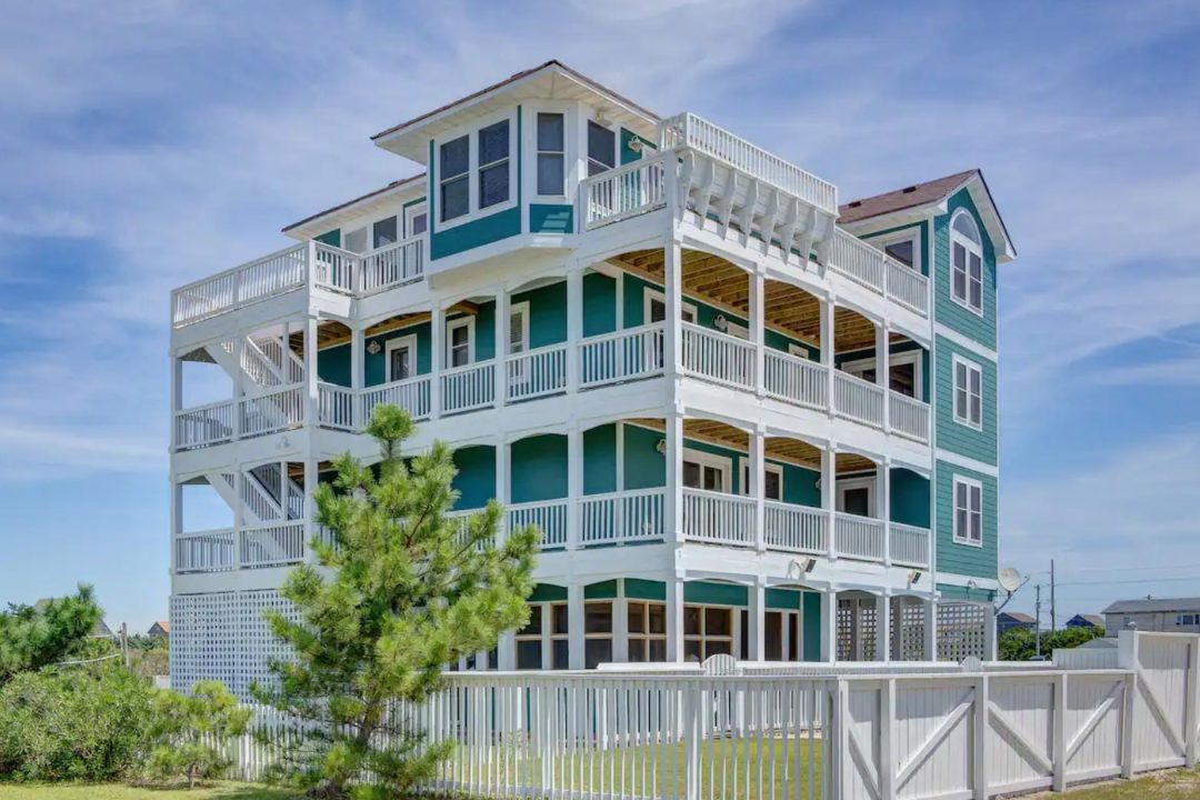 Large four story teal and white coastal home with pool in the Outer Banks