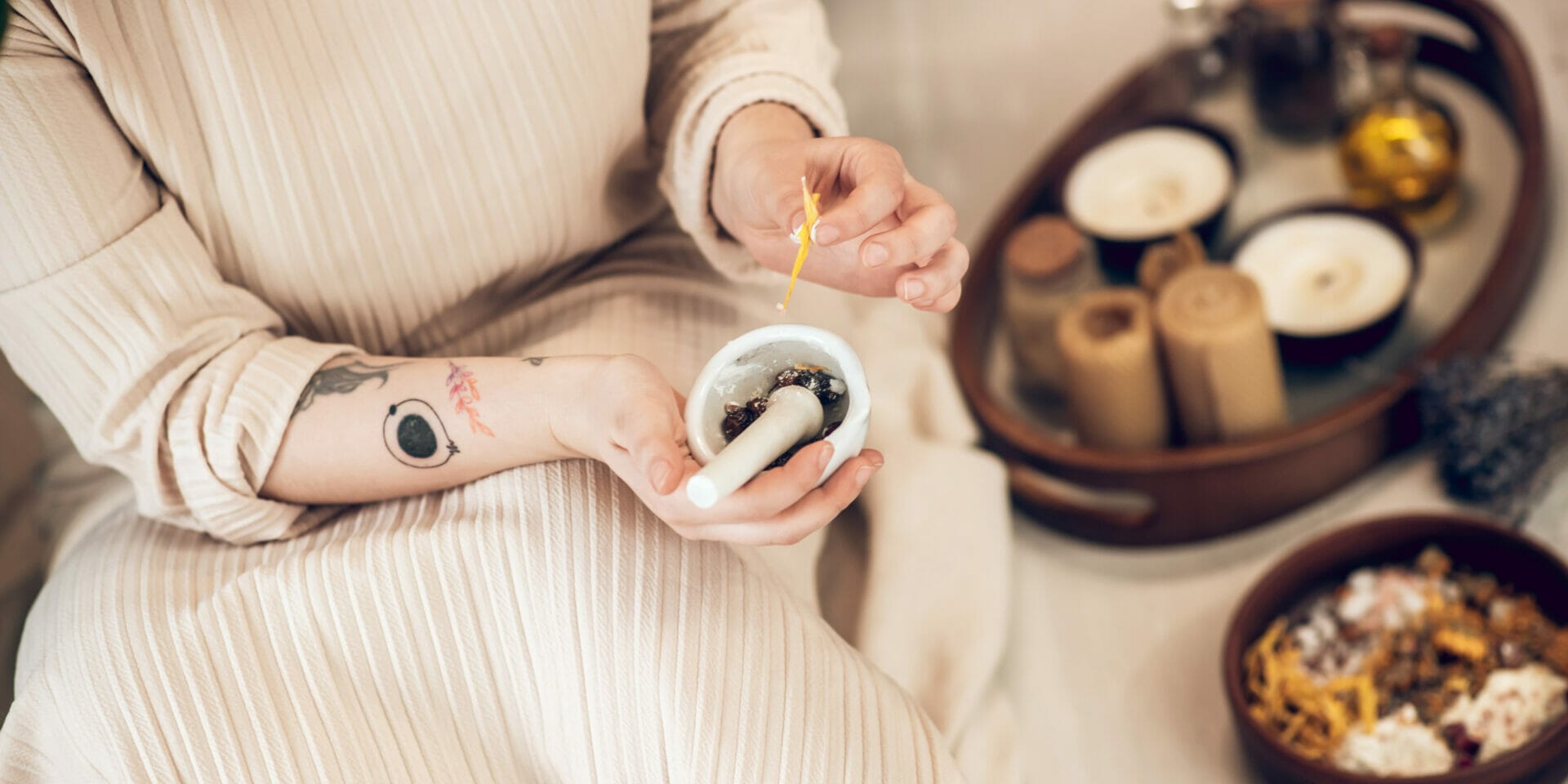 Woman in beige dress, combining herbs for Ayurvedic medicine