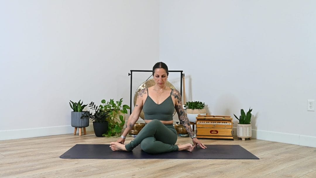 Michelle Young in a green ALO set sitting in gomukasana--cow face pose