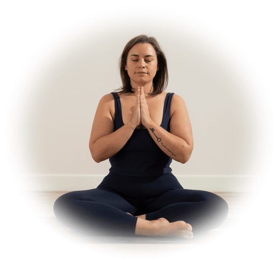 An image of a woman sitting in the lotus position. Her legs are crossed and her eyes are closed.