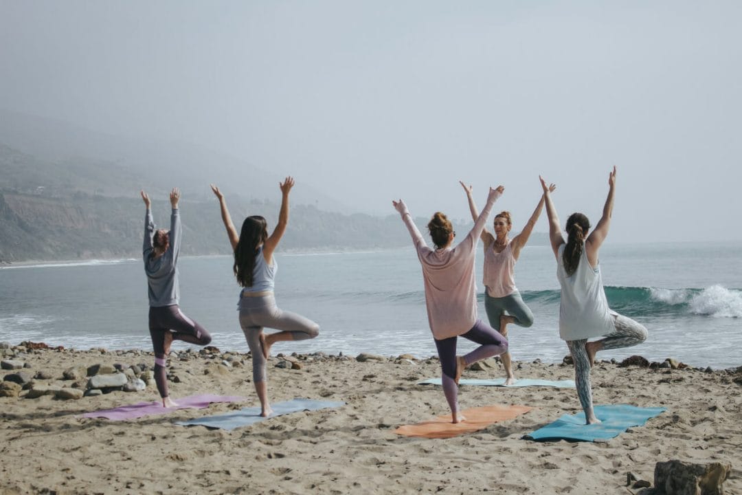 A group of yogis on the beach during a yoga event.