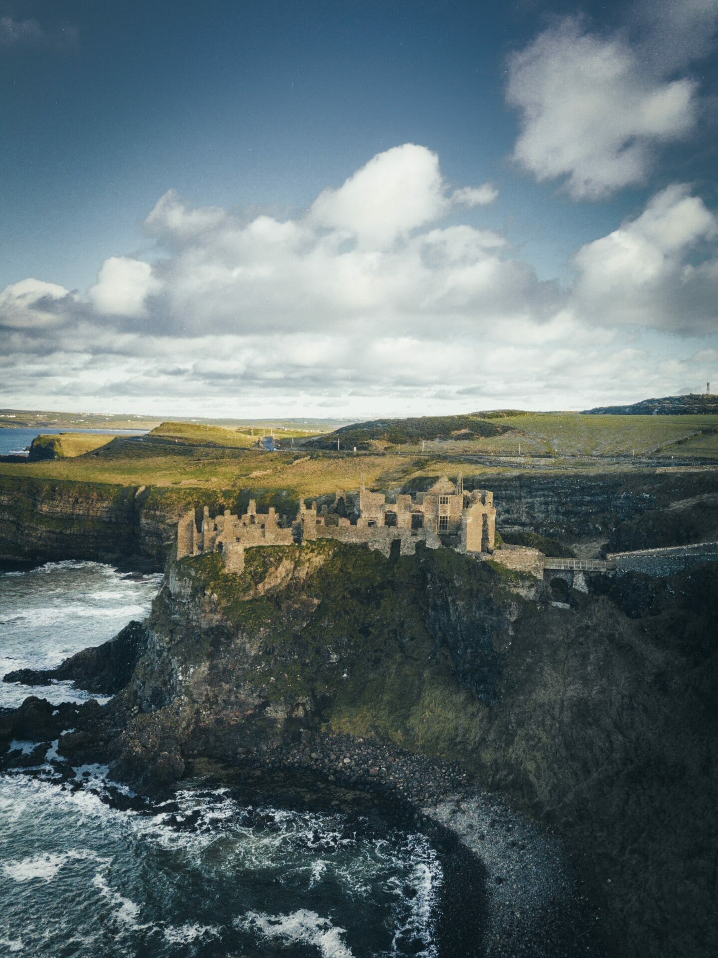 A photo of the hills in Ireland. There is water and a castle visible.