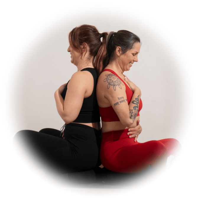 A photo of Michelle and Stephany sittiing in Sukhasana pose while facing each other.