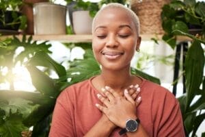 Black woman with hands over heart experiencing peace