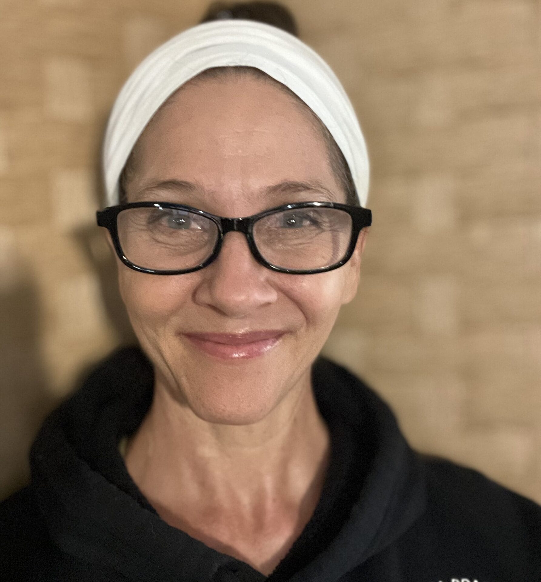 Headshot of Tina Hilbret: Woman with green eyes wearing white turban, wooden mala, and turquoise necklace